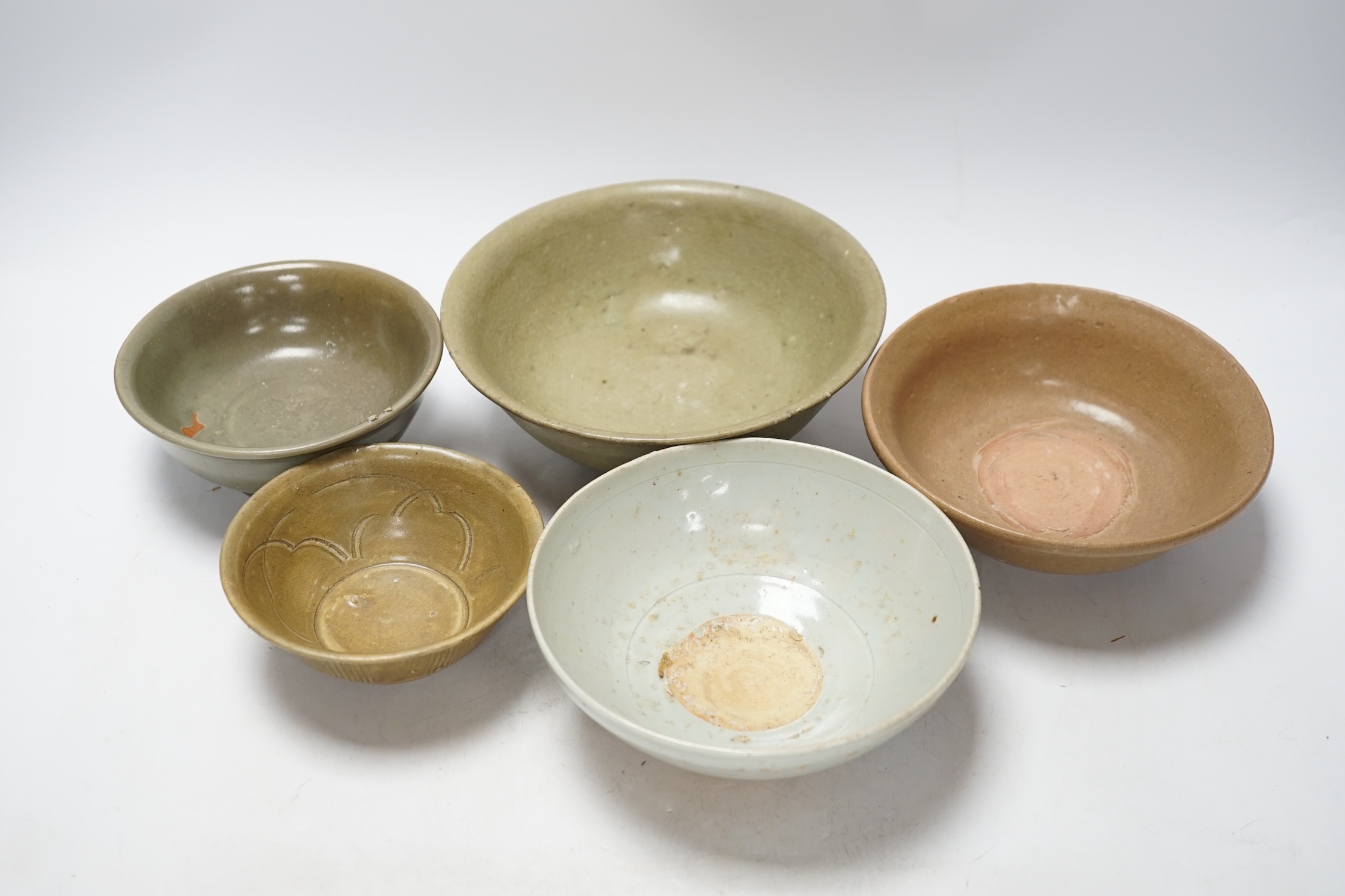 A group of four Chinese Longquan or Yue ware celadon bowls and a Qingbai bowl, Song-Yuan dynasty, largest 20cm diameter (5)